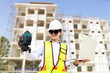© ฺฺฺBoonterm - Female engineer foreman holds laptop computer setup and checks  modern technology tools laser level and vertical marker (Plum Bob) on tripod at construction site, condominium building.
