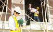 © ฺฺฺBoonterm - Female chief engineer holds laptop inspects modern technology tools laser level and vertical marker (plum bob) on stand at housing construction site working with team architects inspecting house.