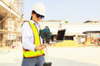 © ฺฺฺBoonterm - Female engineer foreman holds laptop computer setup and checks  modern technology tools laser level and vertical marker (Plum Bob) on tripod at construction site, condominium building.