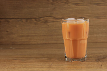 Wall Mural - A Glass of Ice Thai Milk Tea on Wooden Table