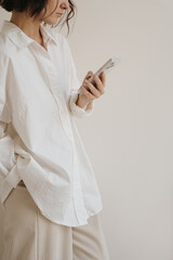 Wall Mural - Woman in white shirt holding mobile phone. Mobile web, internet, social media online surfing