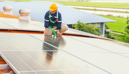 Asian male electrician engineer inspects installation of solar panels on metal roof in industrial factory sitting checking important points each solar panel gives thumbs up through quality inspection.