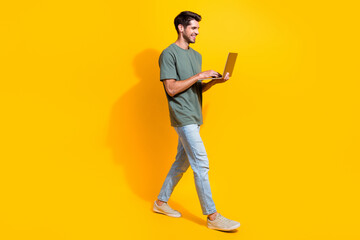 Fototapete - Full length photo of positive cheerful man dressed khaki t-shirt walking texting emails modern gadget isolated yellow color background