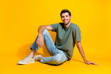 Poster - Full length photo of good mood cheerful man dressed khaki t-shirt sitting smiling isolated yellow color background