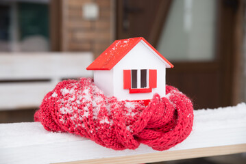 Wall Mural - house in winter - heating system concept and cold snowy weather with model of a house wearing a knitted cap. High quality photo