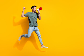 Poster - Full length photo of cool lucky man dressed khaki t-shirt rising fist shouting speaker jumping high empty space isolated yellow color background