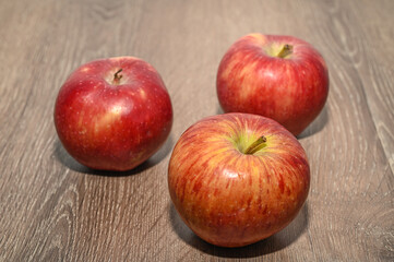 three red apples on a wooden table 2