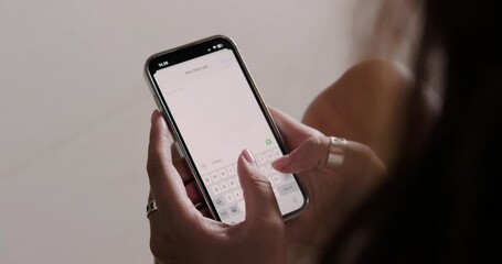 A close-up of the hands of a young woman who is typing a message on the phone with a declaration of love and emoji in the form of hearts. Valentines Day text message to your loved one.