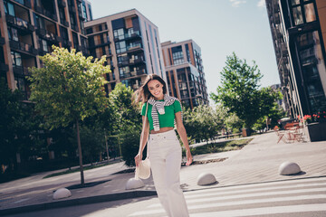 Sticker - Photo of dreamy young charming woman smile wear green t shirt white pants looking asphalt she crosswalk outdoors residential complex