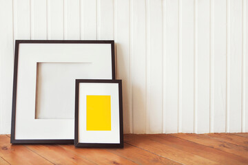 Two posters on the wooden floor by the white wall