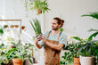 © Iryna - Caucasian man in apron nurturing plants with care at greenery at floral shop. Enjoying his job at cozy flower shop.