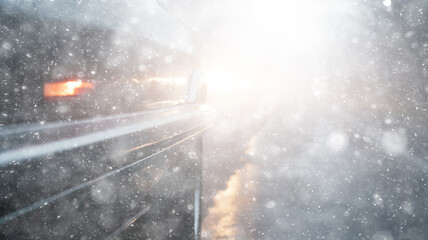 Wall Mural - snowfall, car, background in a snowstorm with a copy of the space, the headlights of an oncoming car through a thick snowfall, winter view on the highway, headlight light