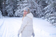 © Viktoriia - A woman in a white jacket and hat standing in the snow.