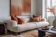 Living room area in gray, beige, orange and peach colors with a sofa, coffe table and modern art on the wall