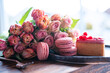 Beautiful pink bouquet of flowers and fine delicacies. Sweet pastries with roses and tulips against blurred light background. Concept for wedding and mother's day.