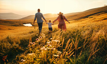 Happy Family Walking Together In The Summer Meadow In The Soft Sunset Light