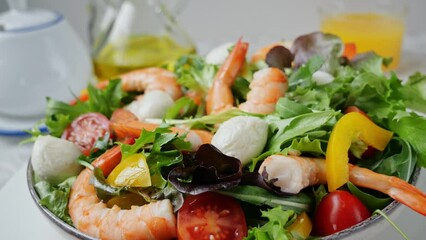 Wall Mural - Vegetarian fresh salad with shrimps mozzarella cheese tomatoes arugula peppers rotating on plate. Close up