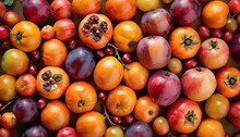  A Close Up Of A Bunch Of Fruit With Many Different Types Of Fruit On It, Including Tomatoes, Tomatoes, And Plums, With Leaves, On A Brown Surface.