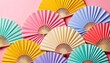  a group of colorful paper fans sitting on top of a pink and yellow wall next to a pink and blue wall and a pink wall with a pink wall in the background.