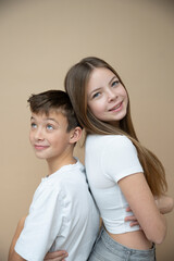 Wall Mural - beautiful pretty 14 years old girl with her cute and cool 11 years old brother in front of brown background, brother and sister love