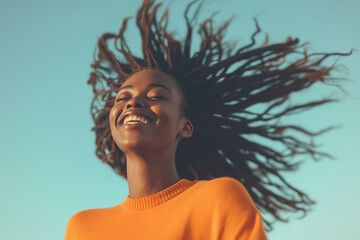 A carefree young African American woman enjoying a moment outdoors on a sunny day with the blue sky in the background. Conveying a positive attitude and a state of well-being.