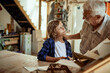 © Marko Geber - Grandfather and grandson working on a model boat in a woodworking workshop