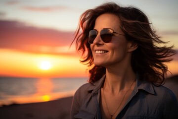 Wall Mural - Portrait of a joyful woman in her 40s wearing a trendy sunglasses against a stunning sunset beach background. AI Generation