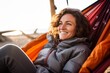 Portrait of a blissful woman in her 30s sporting a quilted insulated jacket against a relaxing hammock on the beach background. AI Generation