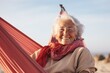 Portrait of a blissful elderly woman in her 90s wearing a windproof softshell against a relaxing hammock on the beach background. AI Generation
