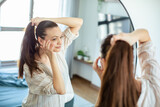 Fototapeta  - Woman styling her ponytail in the mirror at home