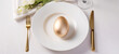 golden easter egg on a white plate, gold cutlery