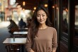 Portrait of a cheerful asian woman in her 20s showing off a lightweight base layer against a bustling restaurant background. AI Generation