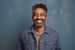 Portrait of a grinning indian man in his 40s sporting a rugged denim jacket against a pastel or soft colors background. AI Generation