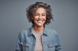 © CogniLens - Portrait of a smiling woman in her 50s sporting a rugged denim jacket against a pastel or soft colors background. AI Generation