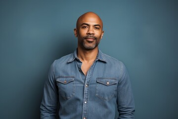 portrait of a content afro-american man in his 40s sporting a versatile denim shirt against a solid 