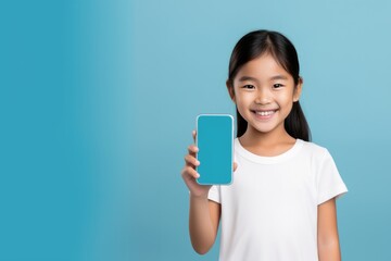 Happy kid tween teen asian girl holding phone smartphone mock up showing white blank display for advertising