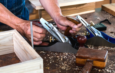 Close up carpenter man working with electric planer in carpentry work place