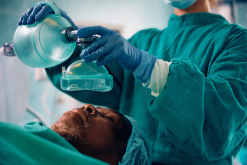 Wall Mural - Close up of anesthesiologist using oxygen mask on patient during surgical procedure in hospital.