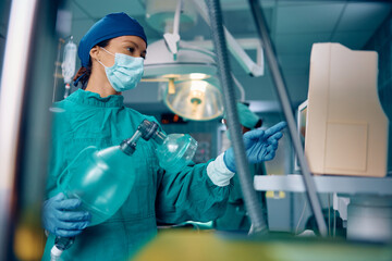 Wall Mural - Female anesthesiologist looking at monitor in operating room in hospital.