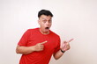 © ArvStd - Wow shocked young asian man standing while pointing presenting something sideways on blank space