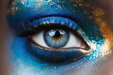 Fototapeta  - A close-up of a human eye with artistic blue and gold makeup.