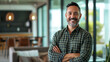 © MP Studio - Cheerful middle-aged man with a beard, standing with his arms crossed in a modern office