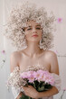 Portrait of sensual blond woman with flowers. Beautiful girl with flowers in her hair. Summer Beauty. Art in a contemporary style. A gypsophila wreath on a white background. Perfume, cosmetics concept