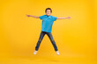 © Prostock-studio - Joyful boy jumping with arms outstretched, yellow backdrop