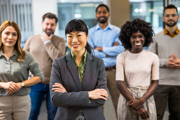 Asian boss standing in front of her colleagues in the office