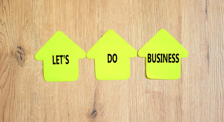 let is do business symbol. Concept words let is do business on beautiful yellow paper houses. Beautiful wooden table wooden background. let is do business concept. Copy space.