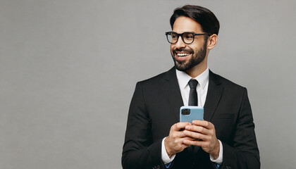 Wall Mural - Adult employee business man corporate lawyer he wear classic formal black suit shirt tie work in office hold use mobile cell phone look aside on area isolated on plain grey background studio portrait