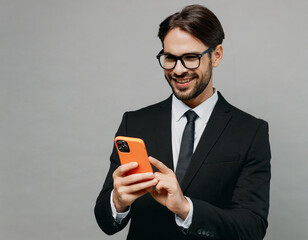 Wall Mural - Adult happy fun successful employee business man corporate lawyer wear classic formal black suit shirt tie work in office hold in hand use mobile cell phone isolated on plain grey background studio