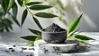 Presented on a white podium adorned with green leaves, the activated bamboo charcoal extract provides numerous advantages for the skin.