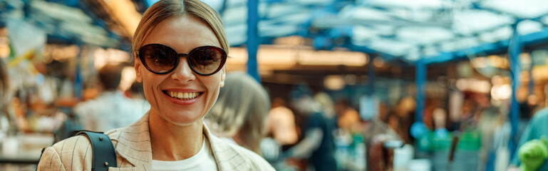 Smiling mature woman is having a takeaway fast food lunch on food market and drink coffee